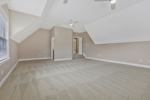 additional living space with light colored carpet, ceiling fan, and vaulted ceiling