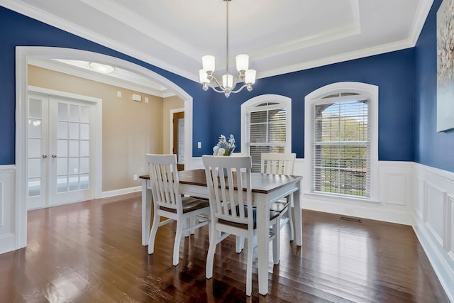 dining room featuring dark hardwood / wood-style flooring, an inviting chandelier, a raised ceiling, and crown molding