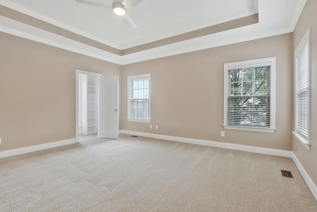 carpeted empty room with ornamental molding, ceiling fan, and a tray ceiling