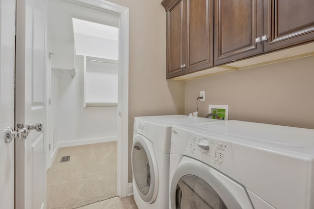 clothes washing area with cabinets, light carpet, and separate washer and dryer