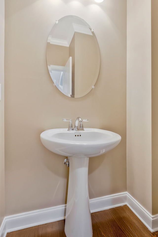 bathroom featuring hardwood / wood-style flooring, crown molding, and sink