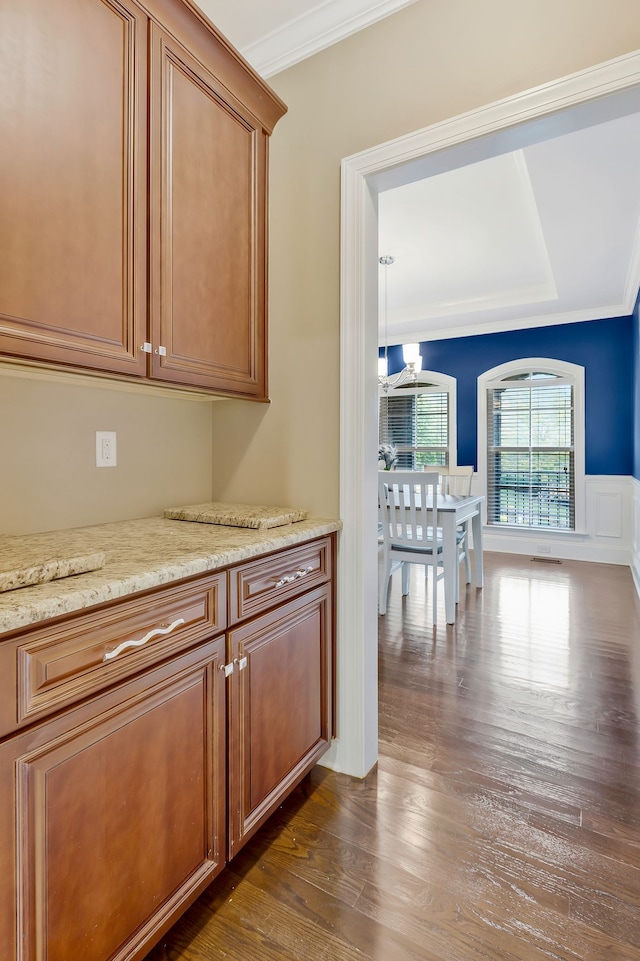 interior space featuring dark hardwood / wood-style flooring, light stone countertops, and ornamental molding