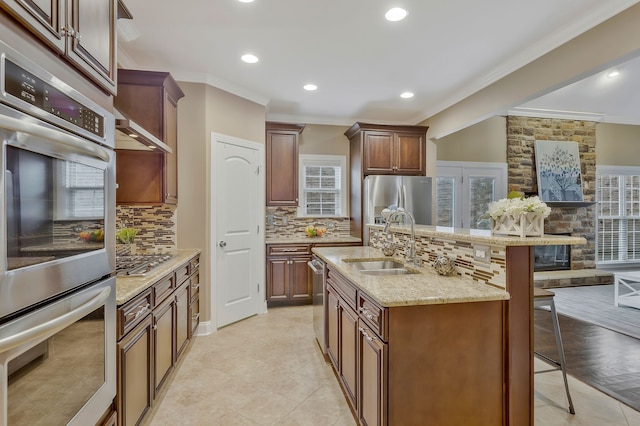 kitchen with an island with sink, ornamental molding, a breakfast bar, and tasteful backsplash