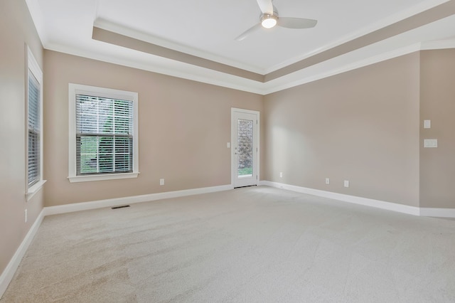 unfurnished room with ceiling fan, light colored carpet, crown molding, and a tray ceiling