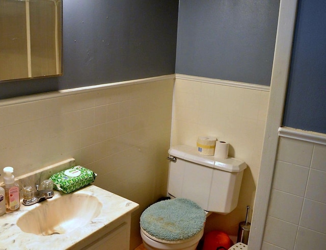 bathroom featuring vanity, tile walls, and toilet