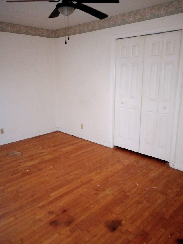 unfurnished bedroom featuring a closet, hardwood / wood-style flooring, and ceiling fan