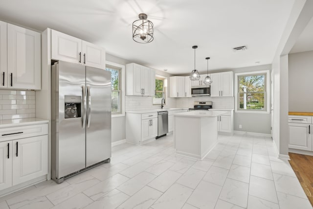 kitchen with white cabinets, appliances with stainless steel finishes, and backsplash