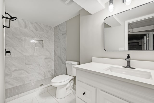 bathroom featuring toilet, vanity, and tiled shower