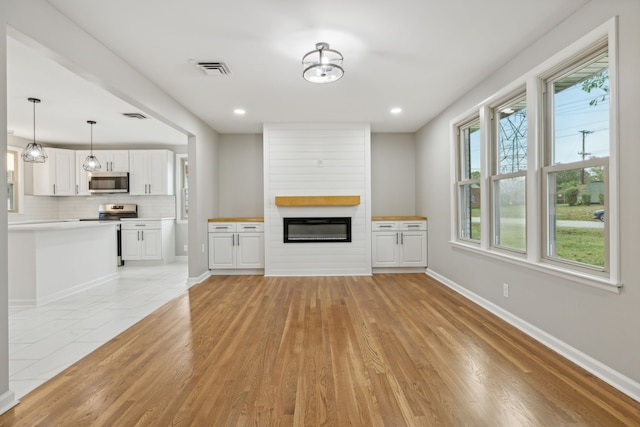 unfurnished living room featuring light wood-type flooring and a fireplace