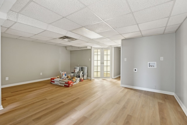 interior space featuring light hardwood / wood-style flooring, french doors, and a drop ceiling