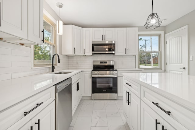 kitchen with appliances with stainless steel finishes, sink, decorative light fixtures, and plenty of natural light