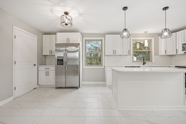 kitchen with white cabinetry, sink, stainless steel fridge, pendant lighting, and decorative backsplash