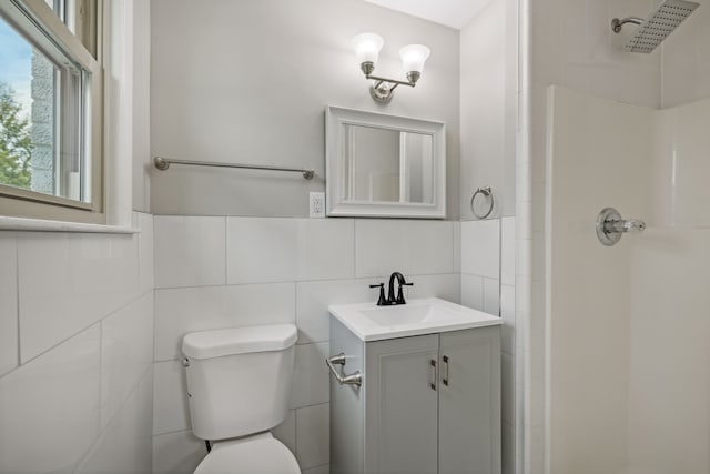 bathroom featuring tile walls, vanity, toilet, and a shower