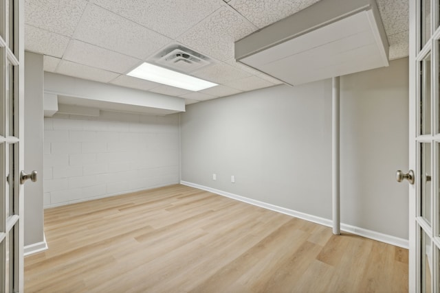 basement with hardwood / wood-style floors and a paneled ceiling