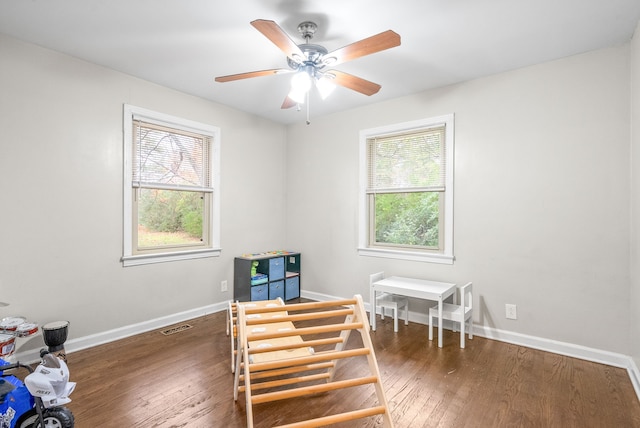 bedroom featuring ceiling fan, multiple windows, and dark hardwood / wood-style flooring