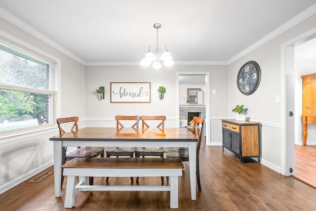 dining room featuring a fireplace, crown molding, dark hardwood / wood-style flooring, and a notable chandelier