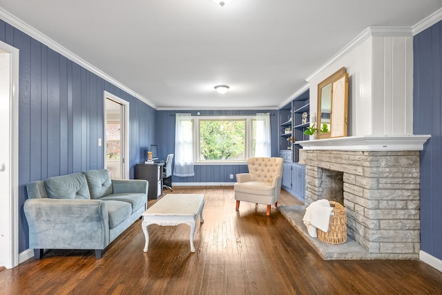 living room featuring ornamental molding, built in features, dark hardwood / wood-style floors, and a fireplace