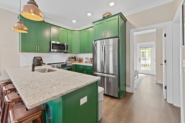 kitchen with stainless steel appliances, sink, kitchen peninsula, a kitchen breakfast bar, and hanging light fixtures