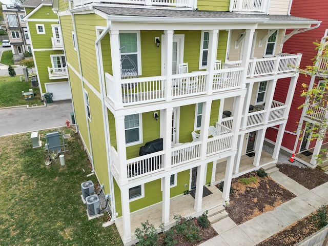 back of property with covered porch, central AC, and a balcony