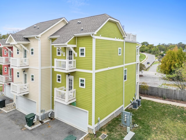 view of side of property with a garage, a yard, and a balcony