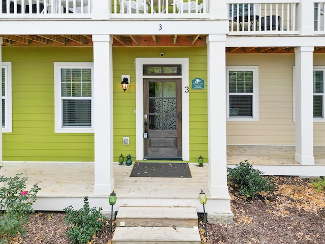 view of exterior entry with a balcony and covered porch