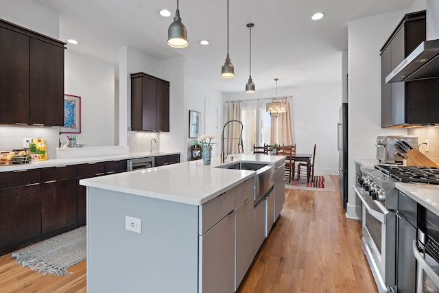 kitchen with dark brown cabinetry, a kitchen island with sink, high quality appliances, and decorative light fixtures