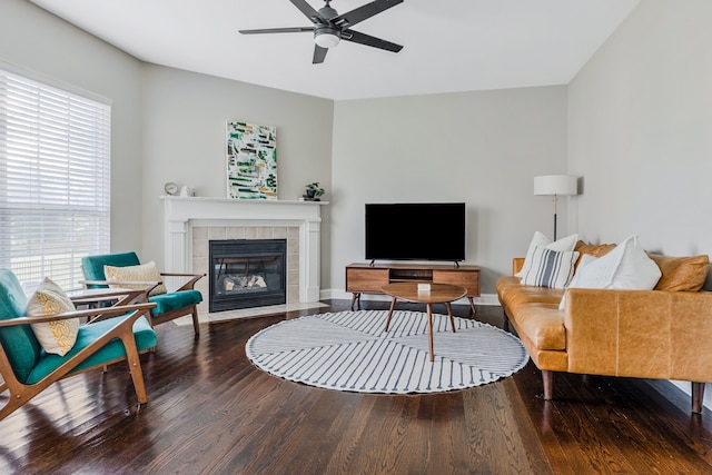 living room featuring hardwood / wood-style floors, a tiled fireplace, and ceiling fan