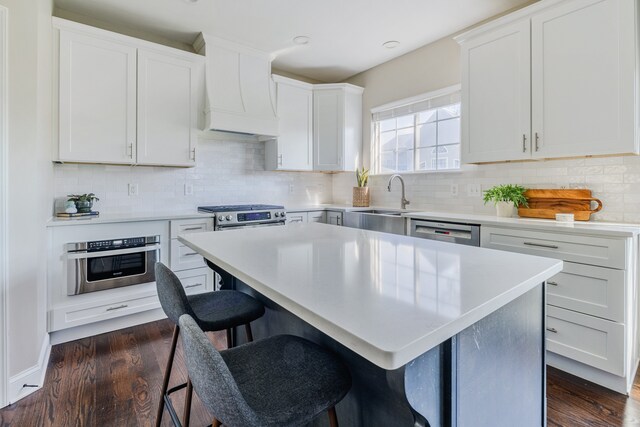 kitchen with white cabinetry, dark hardwood / wood-style flooring, sink, and a center island