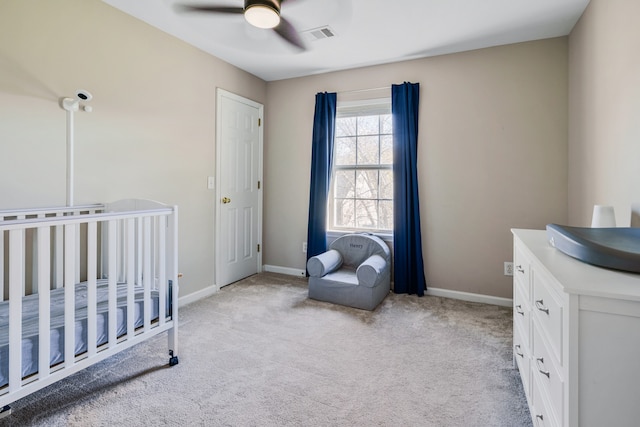 bedroom featuring a crib, light colored carpet, and ceiling fan