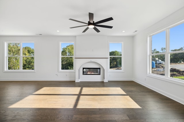 unfurnished living room featuring a wealth of natural light, ceiling fan, and dark hardwood / wood-style flooring