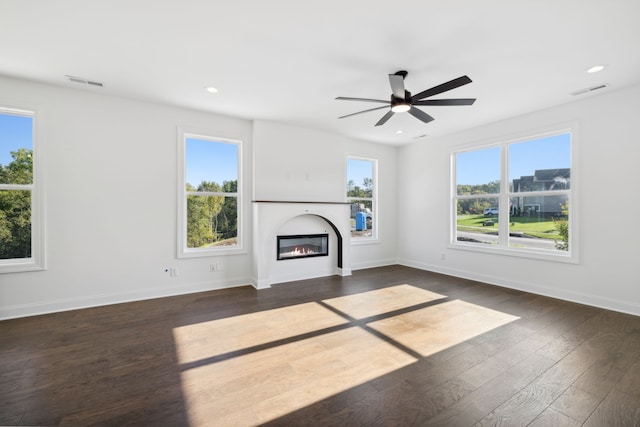 unfurnished living room with ceiling fan, plenty of natural light, and dark hardwood / wood-style flooring