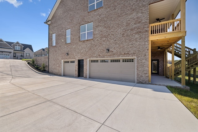 view of side of home featuring a garage, ceiling fan, and a balcony