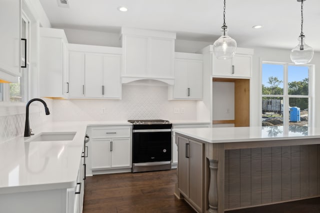 kitchen with white cabinetry, dark wood-type flooring, stainless steel range oven, and decorative light fixtures