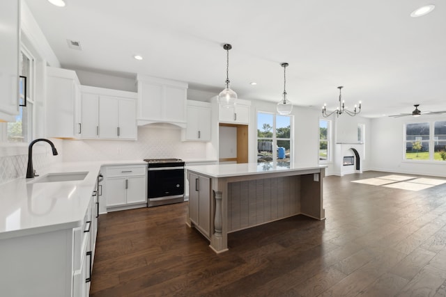 kitchen with white cabinetry, sink, stainless steel electric range oven, a center island, and dark hardwood / wood-style flooring