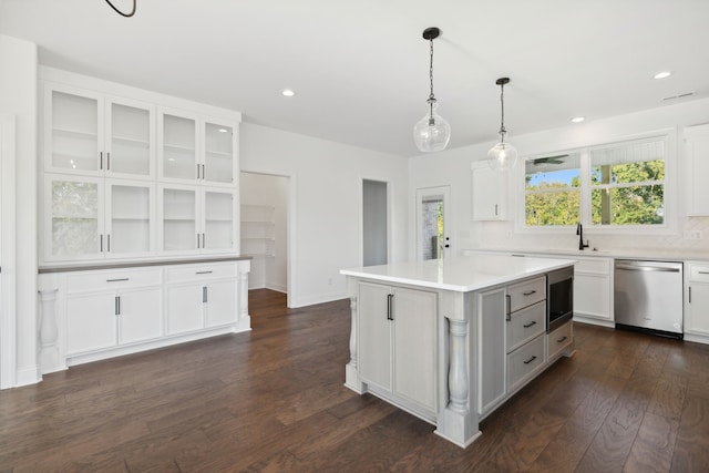 kitchen featuring a kitchen island, white cabinetry, dark hardwood / wood-style flooring, pendant lighting, and stainless steel dishwasher