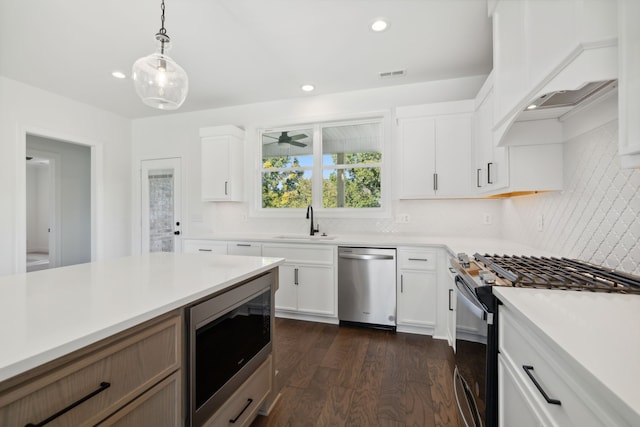 kitchen with white cabinetry, appliances with stainless steel finishes, decorative light fixtures, and dark hardwood / wood-style flooring