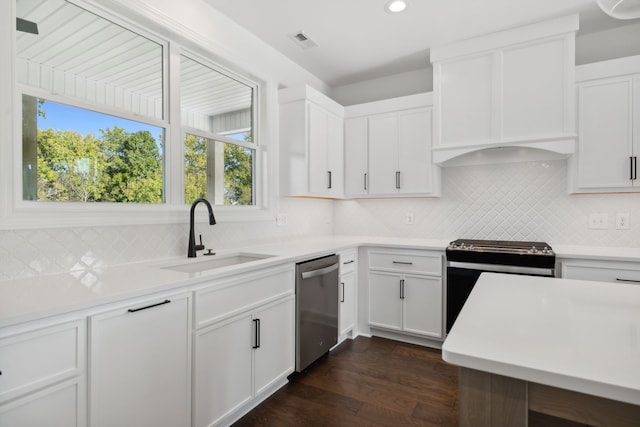 kitchen featuring dark wood-type flooring, sink, backsplash, white cabinetry, and appliances with stainless steel finishes