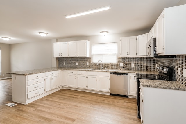 kitchen with stainless steel appliances, white cabinets, light wood-type flooring, and kitchen peninsula