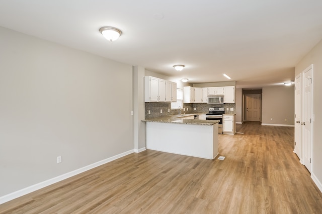 kitchen with white cabinetry, appliances with stainless steel finishes, light wood-type flooring, sink, and kitchen peninsula