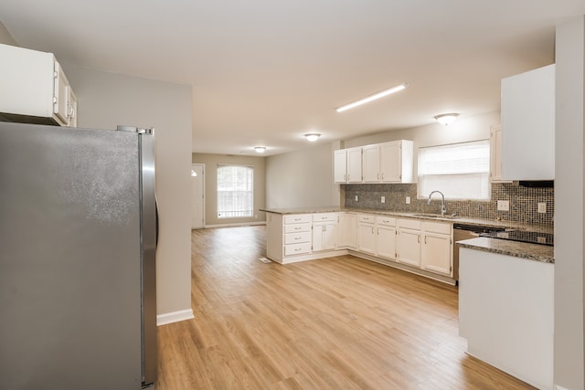 kitchen with stainless steel appliances, white cabinetry, decorative backsplash, sink, and light hardwood / wood-style floors