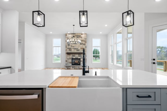 kitchen with a stone fireplace, a wealth of natural light, and pendant lighting