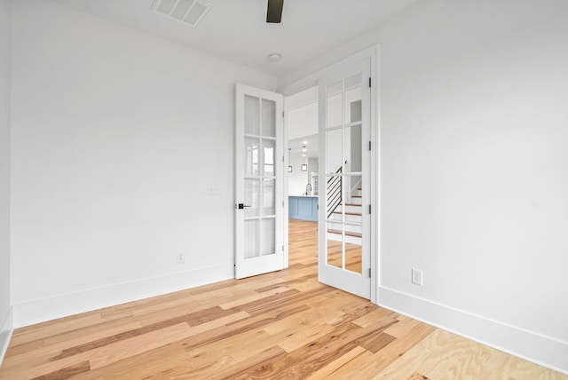 empty room featuring wood-type flooring, ceiling fan, and french doors