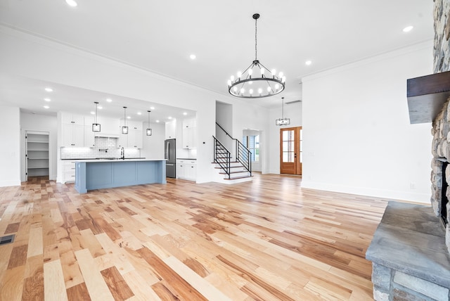 unfurnished living room featuring a fireplace, sink, light hardwood / wood-style flooring, and ornamental molding