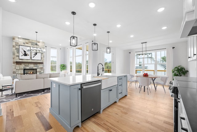 kitchen featuring a center island with sink, appliances with stainless steel finishes, plenty of natural light, hanging light fixtures, and light hardwood / wood-style floors