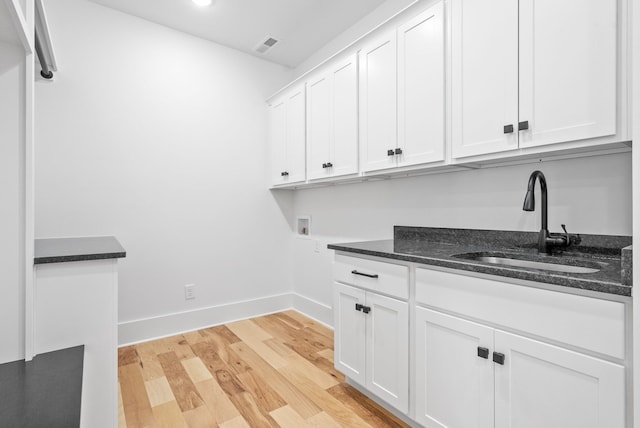 clothes washing area with cabinets, light hardwood / wood-style floors, hookup for a washing machine, and sink