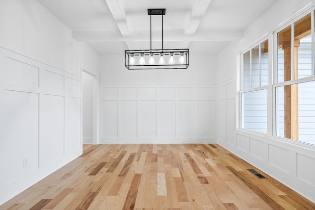 unfurnished dining area featuring light hardwood / wood-style floors, beamed ceiling, a healthy amount of sunlight, and coffered ceiling