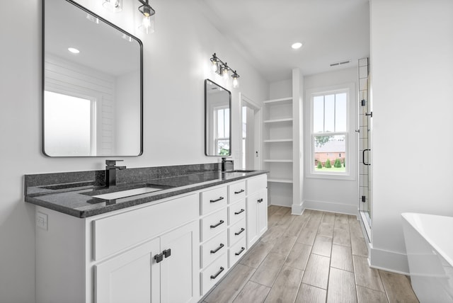 bathroom featuring wood-type flooring, separate shower and tub, and vanity