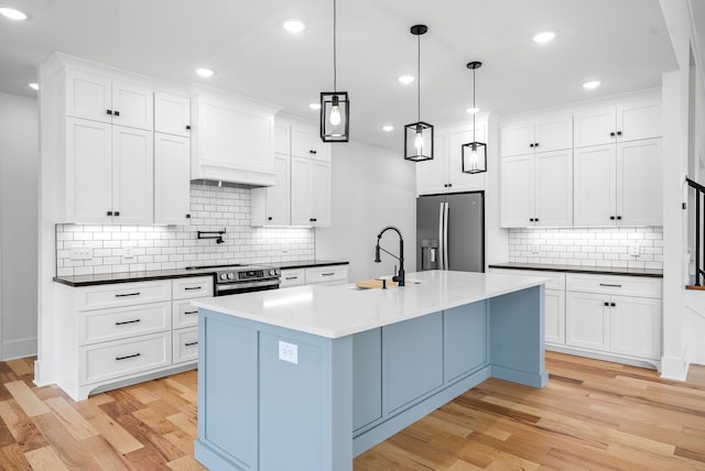 kitchen with stainless steel appliances, decorative light fixtures, light hardwood / wood-style flooring, white cabinets, and decorative backsplash