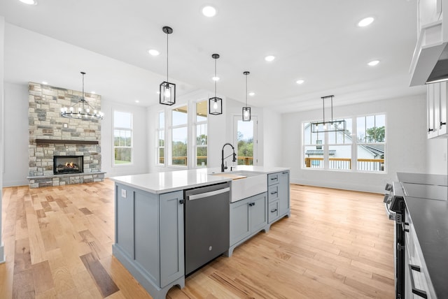 kitchen featuring light hardwood / wood-style flooring, hanging light fixtures, an island with sink, and stainless steel appliances