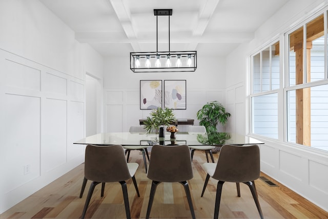 dining room featuring coffered ceiling, light hardwood / wood-style floors, a healthy amount of sunlight, and beam ceiling